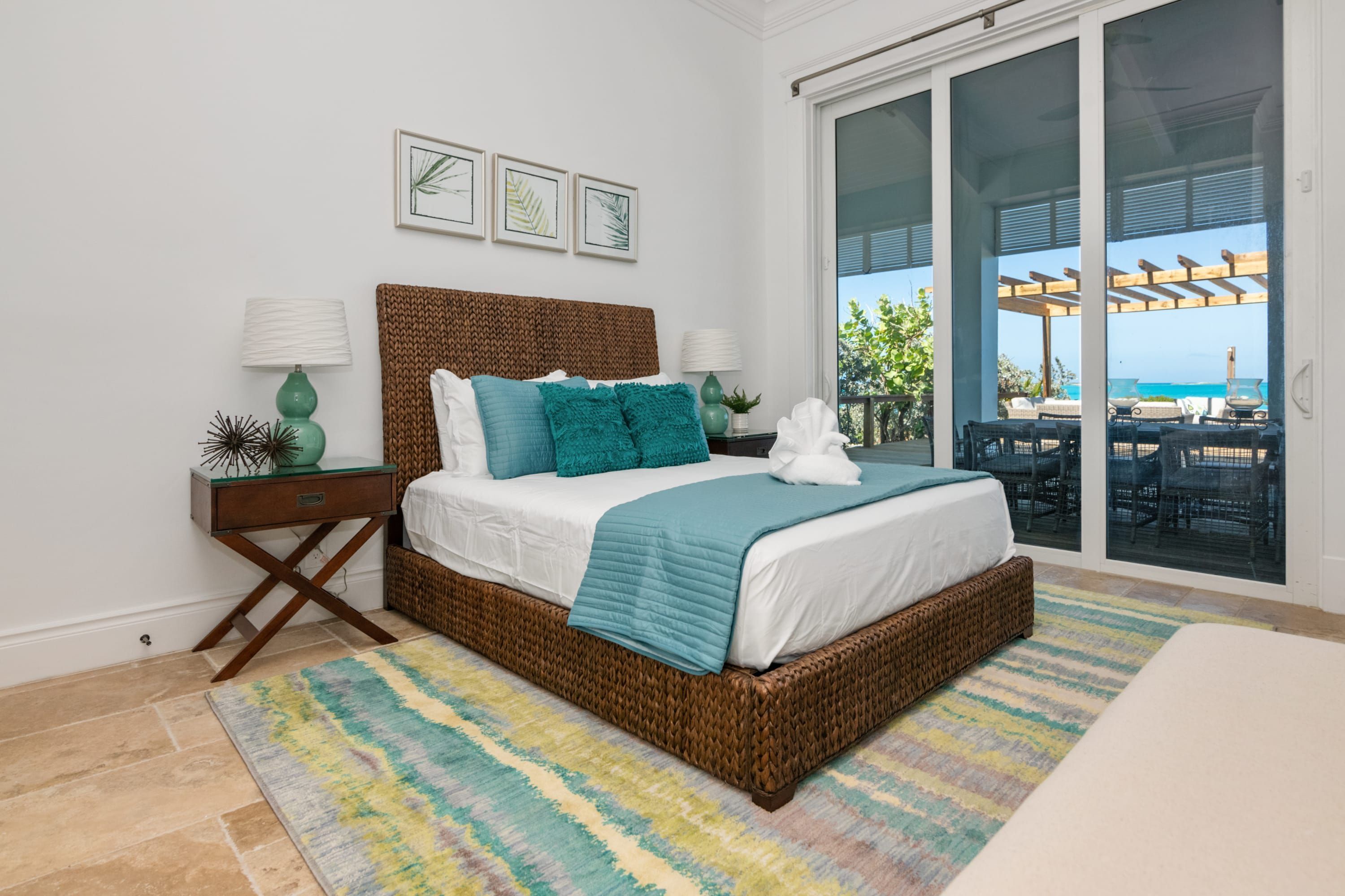 Un dormitorio con una cama grande, vistas al exterior a través de puertas corredizas de vidrio y una mesita de noche con lámpara.