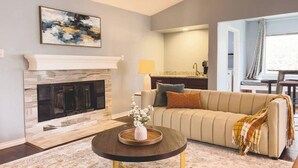 Un salon avec une cheminée, un canapé, une table basse et un tableau au mur.