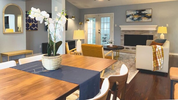 Un salon moderne comprenant un coin repas, une cheminée et un ventilateur de plafond.