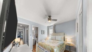 A bedroom with a bed, bedside table, and a ceiling fan. - Sea The Good 2 Bedroom Condo by RedAwning (Carolina Beach)
