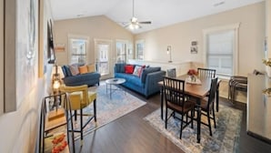 A spacious living area with a blue sofa, a dining table with chairs, and a ceiling fan. - Blue Snapper 3 Bedroom Condo by RedAwning (Carolina Beach)