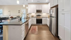 A modern kitchen with white cabinets, stainless steel appliances, and pendant lighting. - Blue Snapper 3 Bedroom Condo by RedAwning (Carolina Beach)