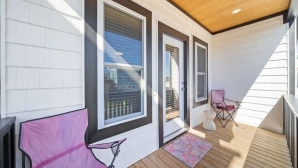 A covered outdoor area with a wooden deck, a pink chair, and a small rug. - Blue Snapper 3 Bedroom Condo by RedAwning (Carolina Beach)