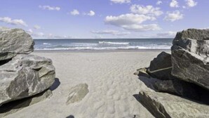 A beach with large rocks in the foreground and a clear view of the ocean. - Beach Bliss 1 Bedroom Condo by RedAwning (Carolina Beach)