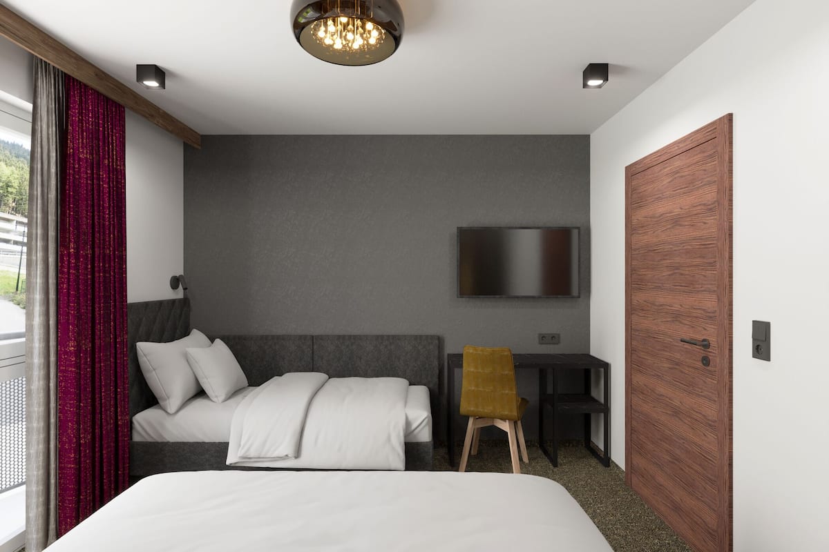 A modern hotel room with a large bed, a desk, a television, and a wooden door.
