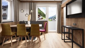 A modern dining area with wooden flooring, a wooden table, and yellow chairs. There are three pendant lights above the table. - Astellina hotel-apart (Ischgl)