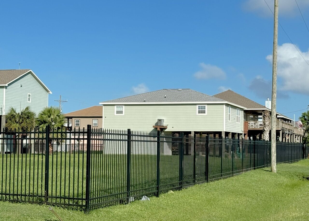 A fenced yard with a house in the background.