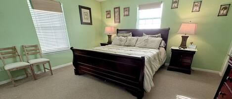 A bedroom with a bed, two nightstands, a chair, a dresser, and a window with blinds.