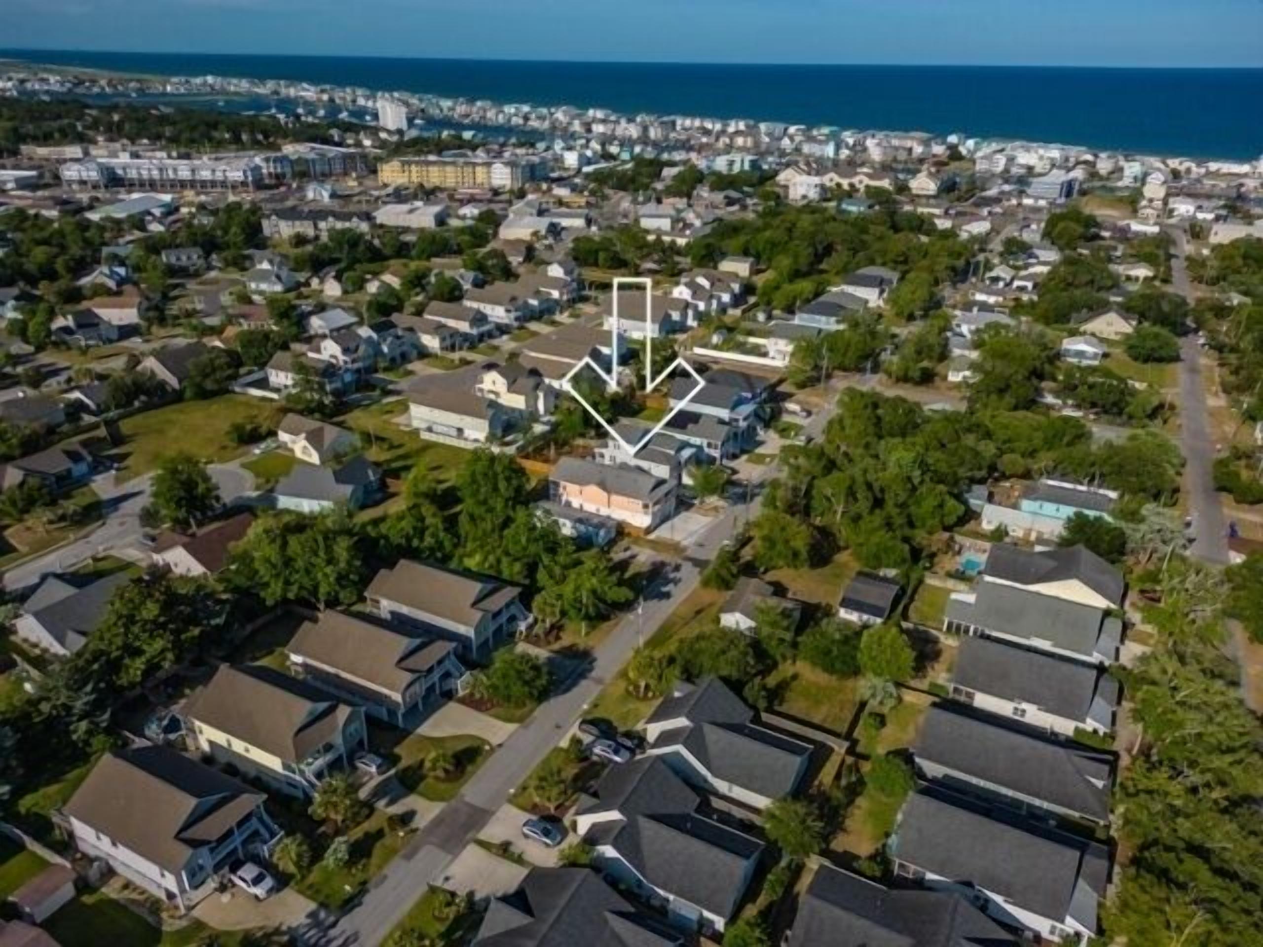 Ett flygbildsfoto av ett bostadsområde med hus, gator och en vattenyta i bakgrunden.
