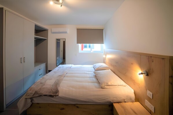 Une chambre à coucher avec un lit, une armoire intégrée et une fenêtre donnant sur un beau paysage.