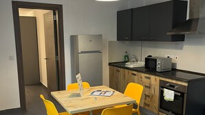 Una cocina compacta con electrodomésticos modernos, un comedor con sillas amarillas y una mesa de madera.