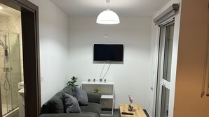 Una sala de estar moderna con un sofá gris, una mesa de centro de madera y un televisor montado en la pared.