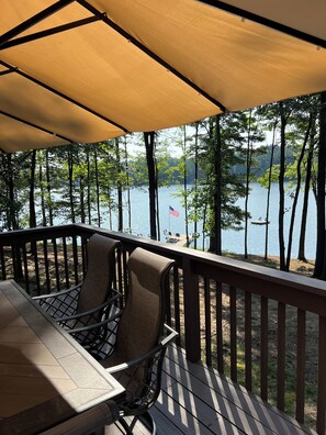 A covered outdoor deck with a table and chairs, overlooking a lake with trees and a flag. - A Private Lake Estate on Eagle River Chain - 1 mi from Downtown (Eagle River)