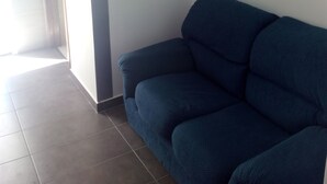 Ett rum med en mörkblå soffa, en vit vägg och en ljusströmbrytare.