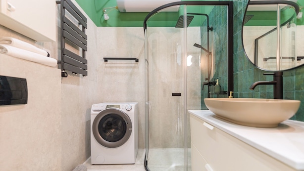 A compact bathroom with a washing machine, a glass shower enclosure, and a large sink. - happy home WOW (Budapest)
