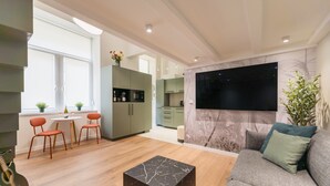 Ein modernes Wohnzimmer mit einem grauen Sofa, einem schwarzen Marmor-Couchtisch und einem an der Wand befestigten Flachbildfernseher.