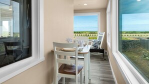 Ein Balkon mit Tisch und Stühlen, Blick auf die Landschaft und ein Fenster zum Himmel.