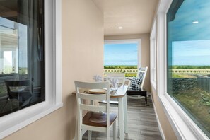 Un balcon avec une table et des chaises, une vue sur le paysage et une fenêtre donnant sur le ciel.