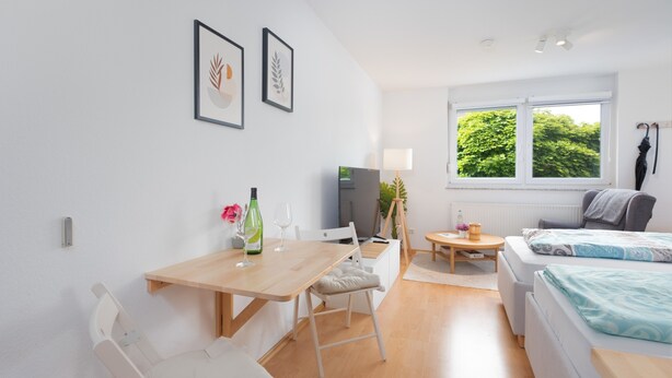 Una habitación moderna con una mesa de comedor de madera, un sofá, una cama y un televisor.