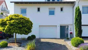 Una casa de dos plantas con fachada blanca, un garaje y un camino de entrada.