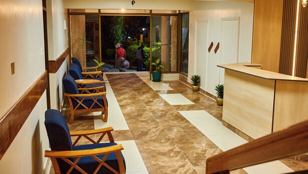 Un hall d’hôtel comprenant un comptoir d’accueil, un espace détente avec des fauteuils et un comptoir d’enregistrement.