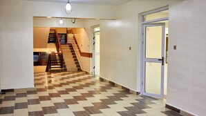 Un couloir doté d’un sol à carreaux, d’un escalier et d’une porte en verre dépoli.