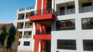Un immeuble à plusieurs étages, doté d’une façade rouge et blanche, de balcons et d’un espace d’entrée abrité.