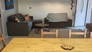 A living room with a sofa, a coffee table, and a dining table. There are two pendant lights hanging from the ceiling. - Modern apartment with incredible views (Le Crès)