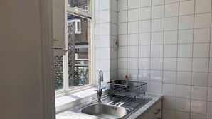 A kitchen with a sink, a dish rack, and a window. - Terraced studio, Baker street (London)