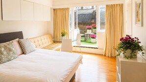 A bedroom with a bed, a sofa, a table, and a view of the outside. - Terraced studio, Baker street (London)