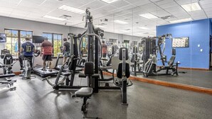 Ett gym med olika träningsmaskiner, en stor spegel och en blå vägg.