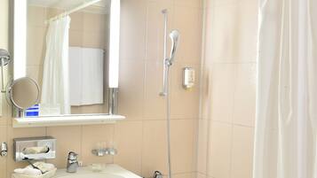 A bathroom with a sink, mirror, shower, and towel rack.