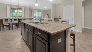 Cocina moderna con armarios oscuros, encimera de granito e iluminación colgante.