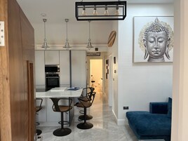 A modern kitchen with a central island, pendant lighting, and a dining area with bar stools.