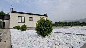 Een modern gebouw met een plat dak, omgeven door witte kiezelstenen en kleine struiken.