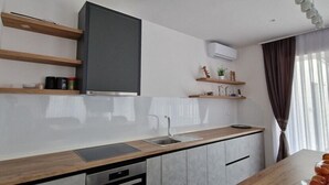 Een moderne keuken met een inbouwoven, een spoelbak en houten planken.