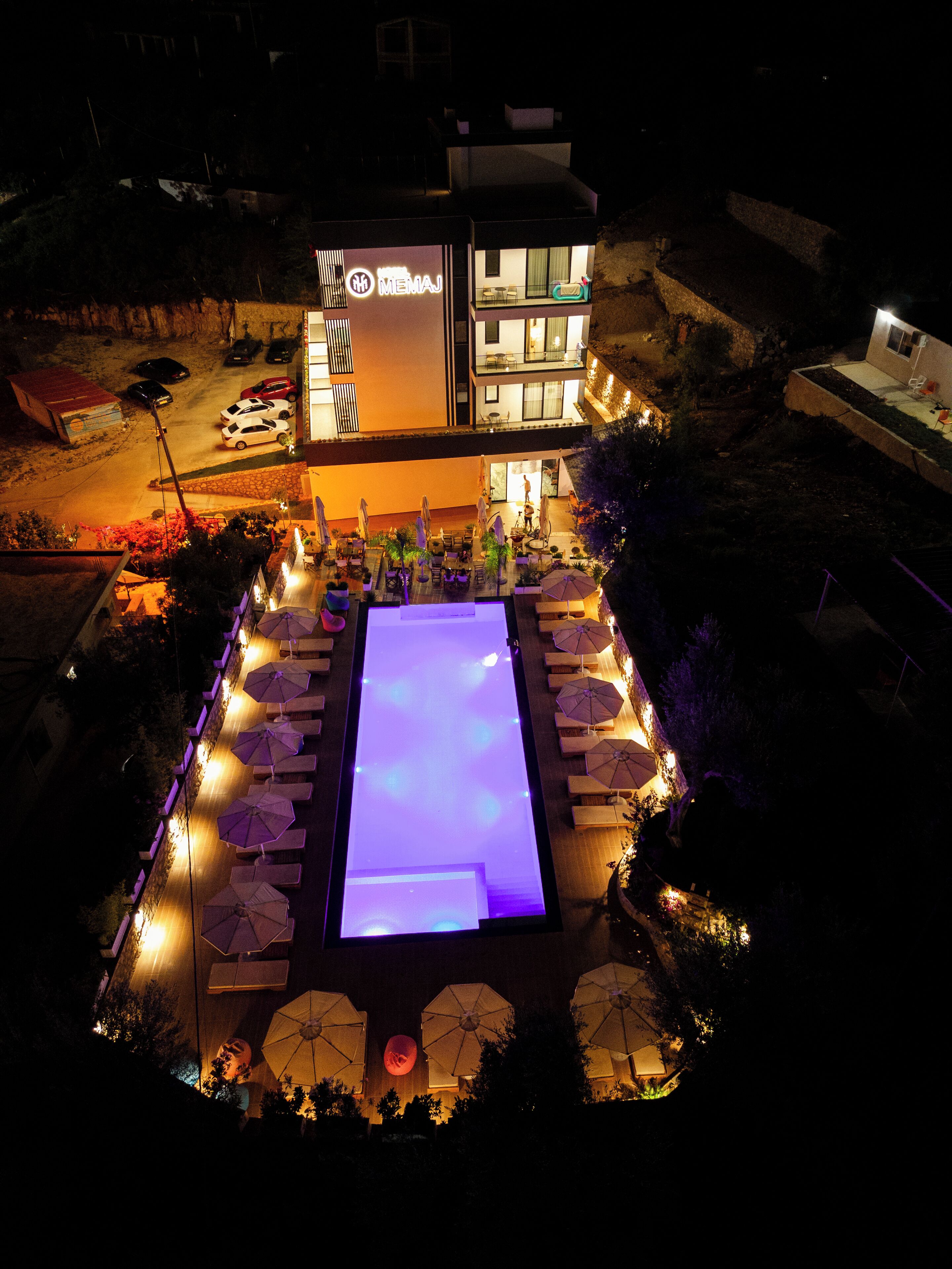 A hotel with a pool area, outdoor seating, and a well-lit entrance.