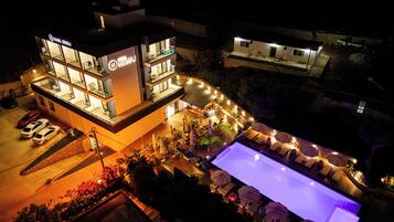 Un hotel con varios pisos, terraza al aire libre y piscina.