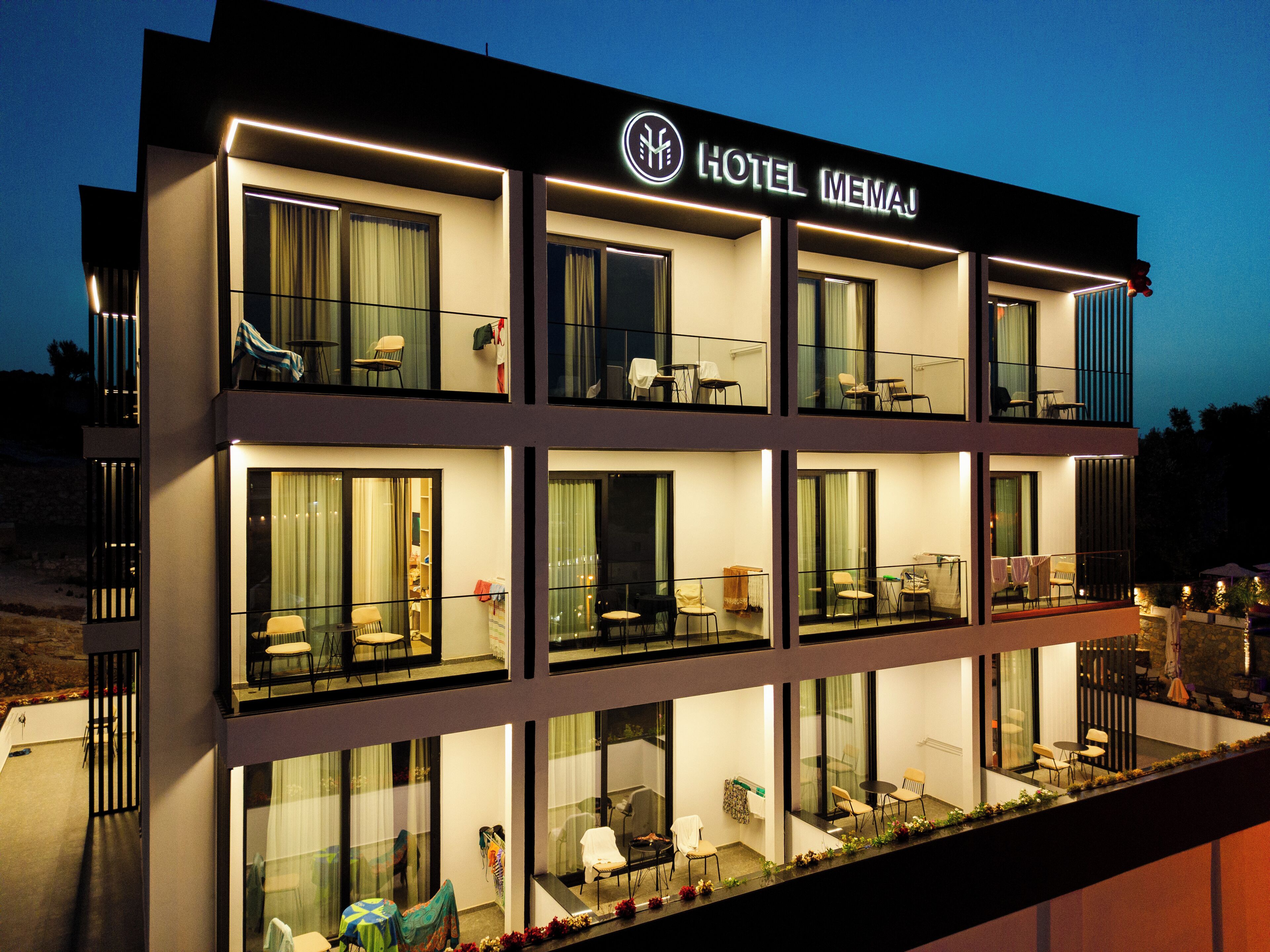 A multi-story hotel with balconies, large windows, and a sign reading "HOTEL MENAJ".