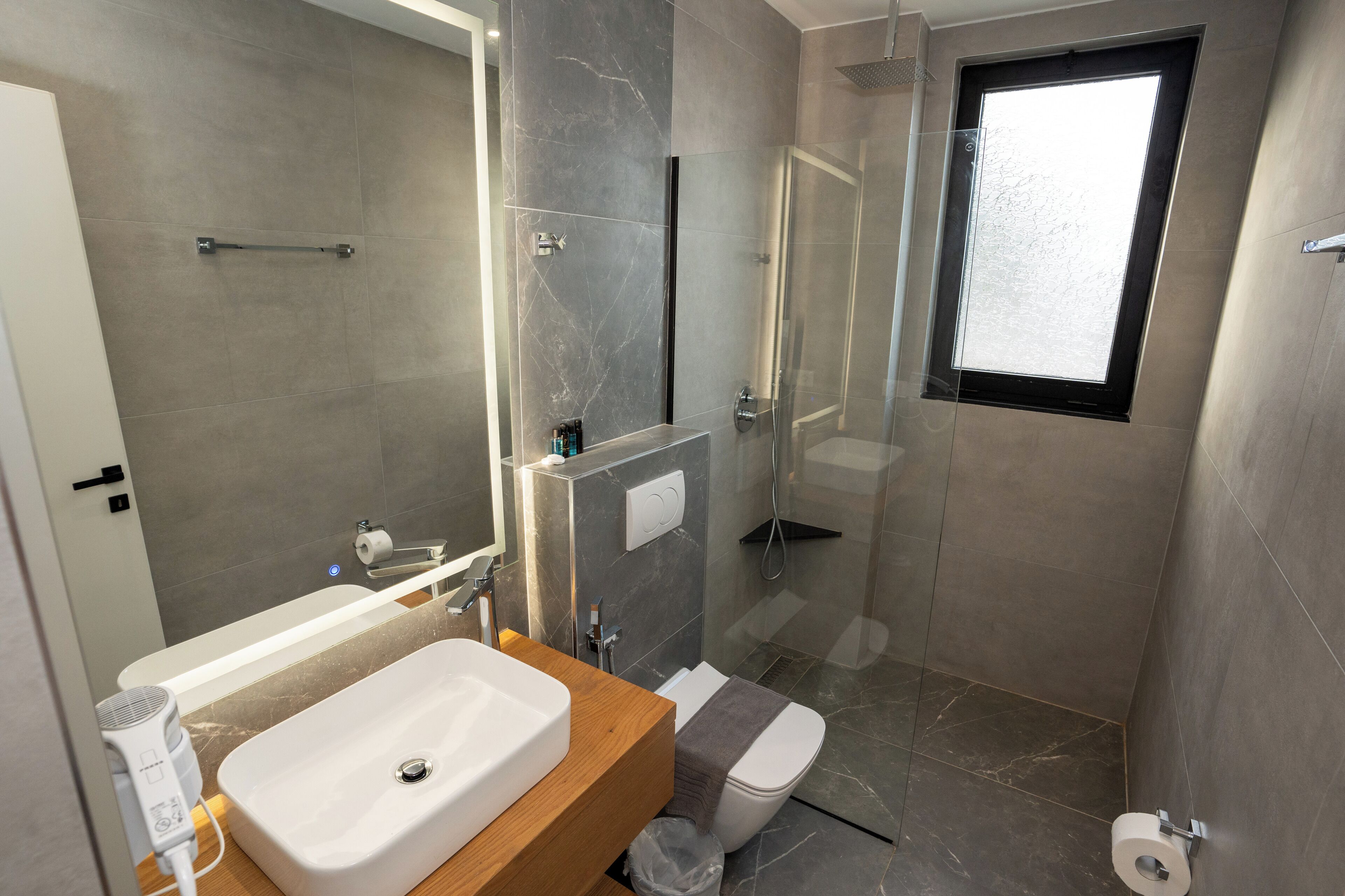 Un baño moderno con lavamanos, inodoro y zona de ducha.