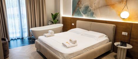 Quarto de hotel moderno com uma cama grande, banheiro privativo, uma mesinha e uma grande obra de arte abstrata na parede.