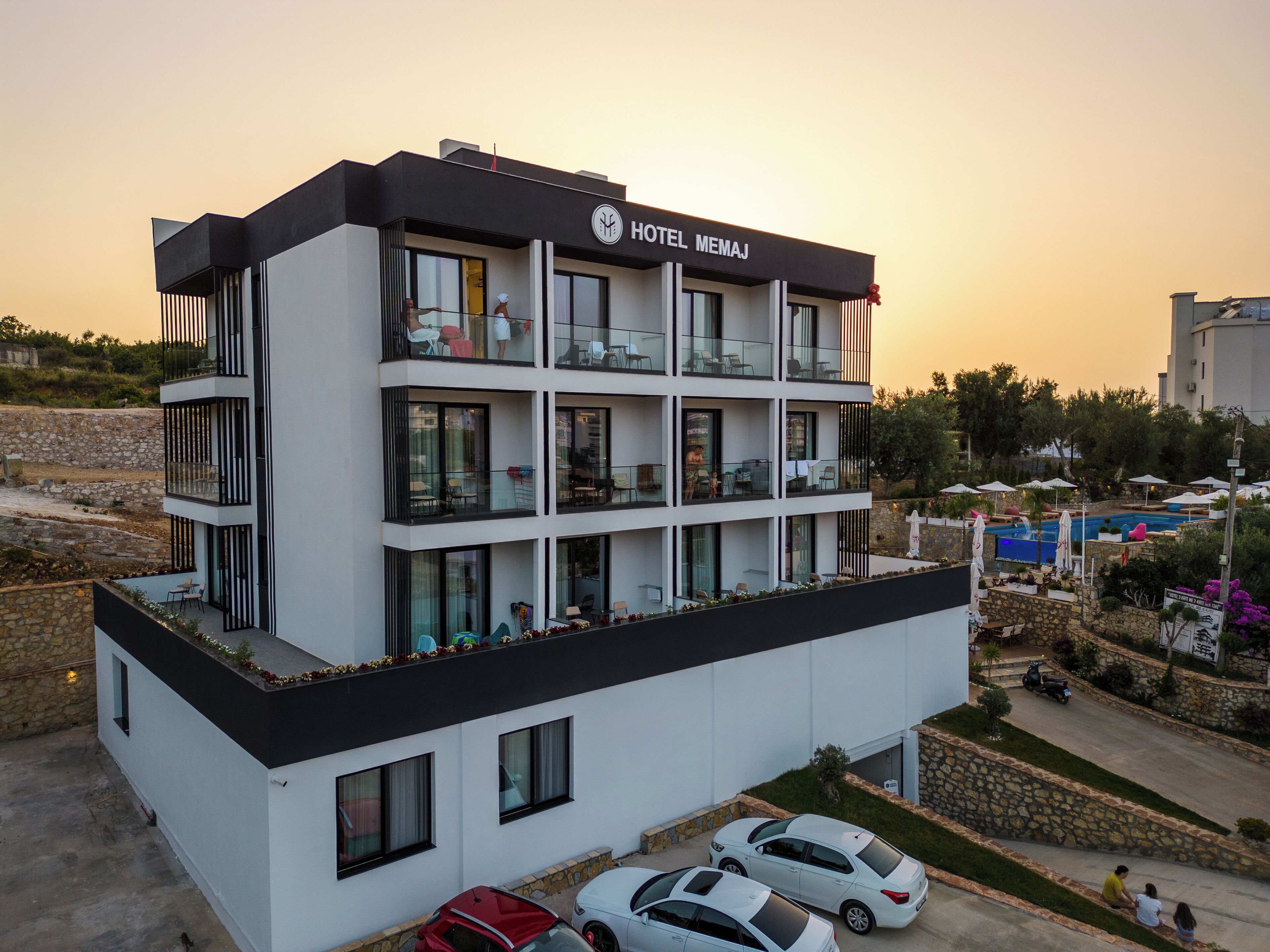 Un hotel moderno con fachada blanco y negro, varios balcones y una zona de piscina.