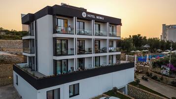Un hotel moderno con fachada blanco y negro, varios balcones y una zona de piscina.