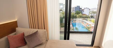 Et hotelværelse med seng, udsigt til en swimmingpool og en balkon.