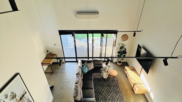 A modern living room with a sofa, a coffee table, and a TV mounted on the wall. -  Modern New Yorker Inspired Townhouse~ Full kitchen-Fast Wifi- Near Bunbury (Australind)