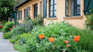 Ein Gebäude mit grünen Fensterläden und ein Garten mit verschiedenen Blumen.