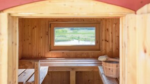Eine Holzsauna mit Blick durch ein Fenster auf ein grünes Feld.