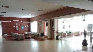 A spacious lobby with a red brick wall, several seating areas, and potted plants. - Intersur Independencia (Termas de Rio Hondo)