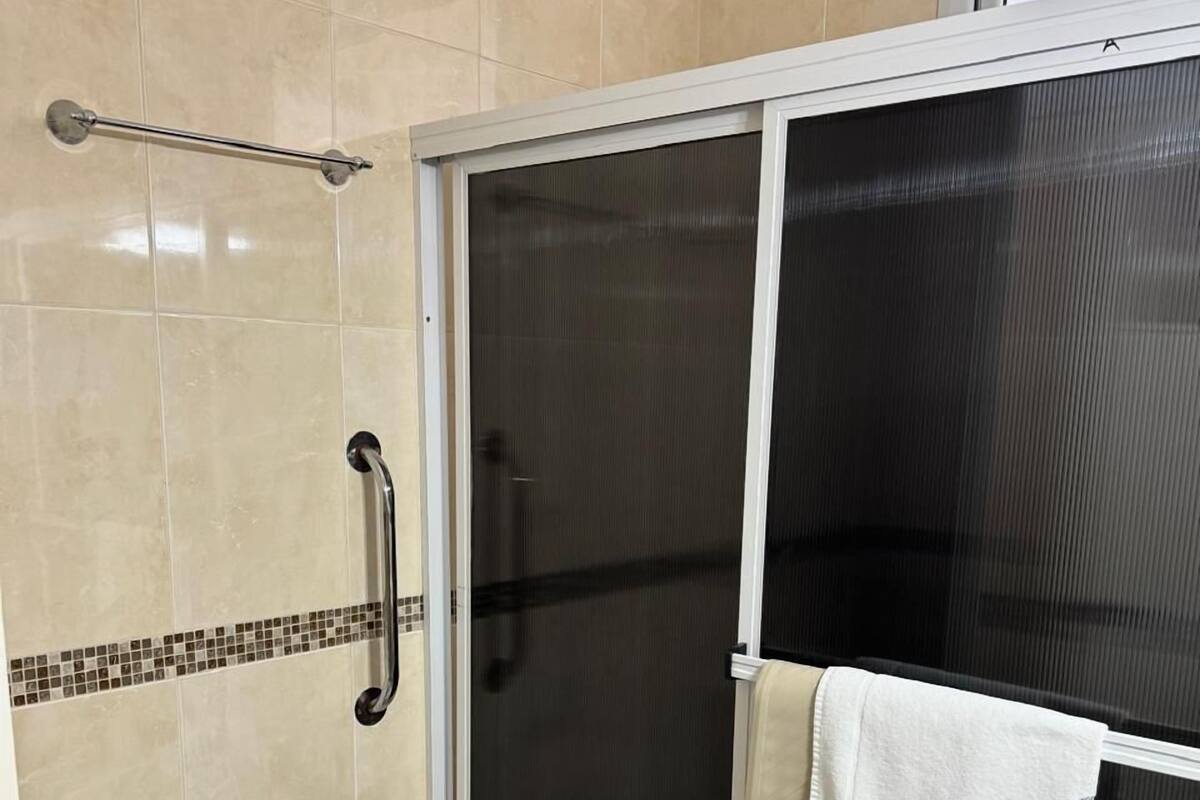 A bathroom with a shower enclosure, a bidet, and a towel rack.