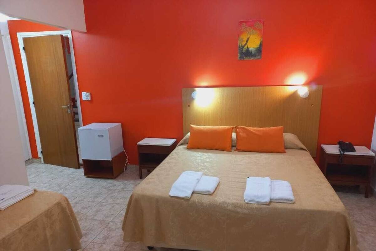 A hotel room with a large bed, two bedside tables, a nightstand, and a small cabinet.